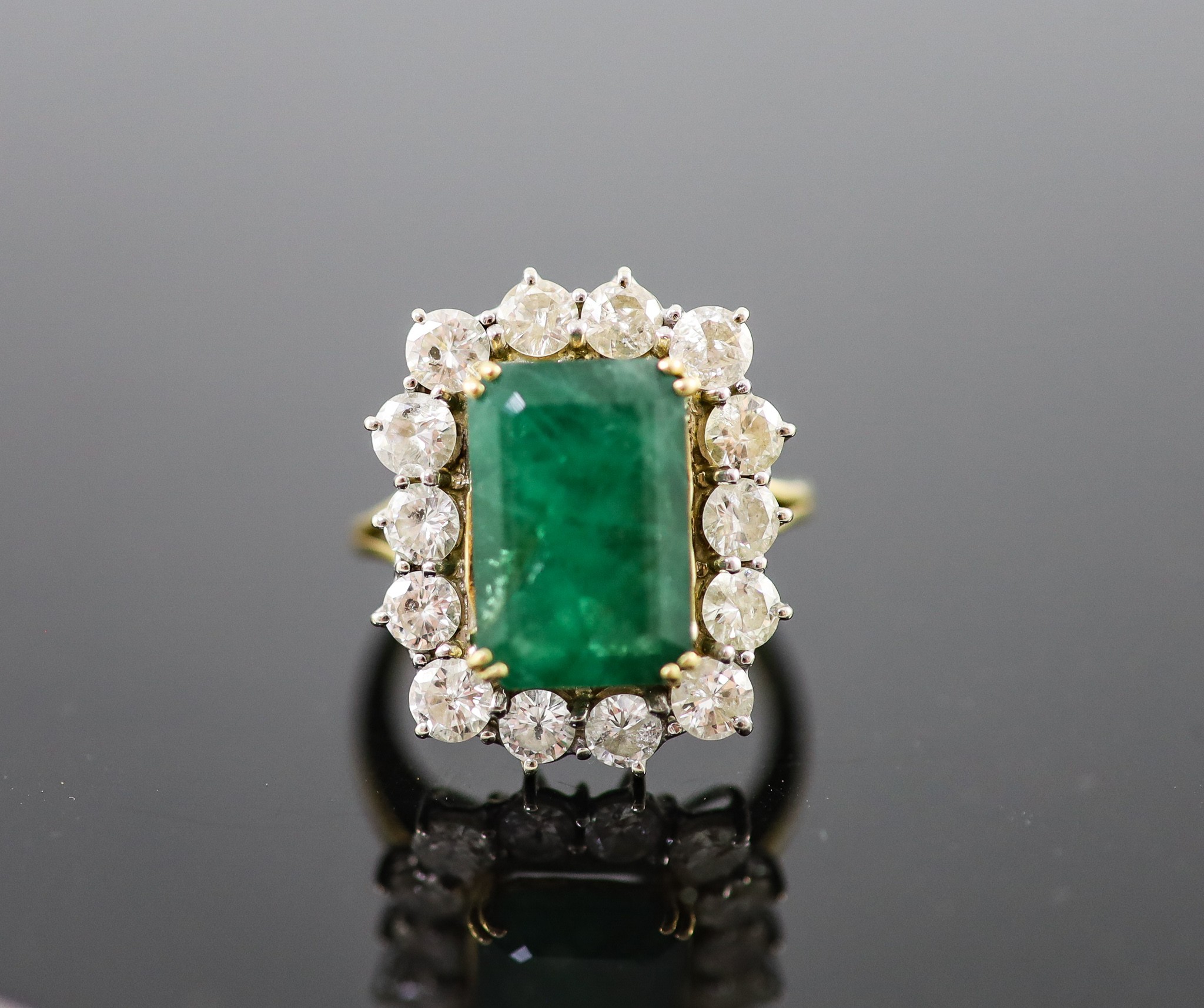 A mid to late 20th century 18ct gold, emerald and diamond set shaped rectangular cluster ring